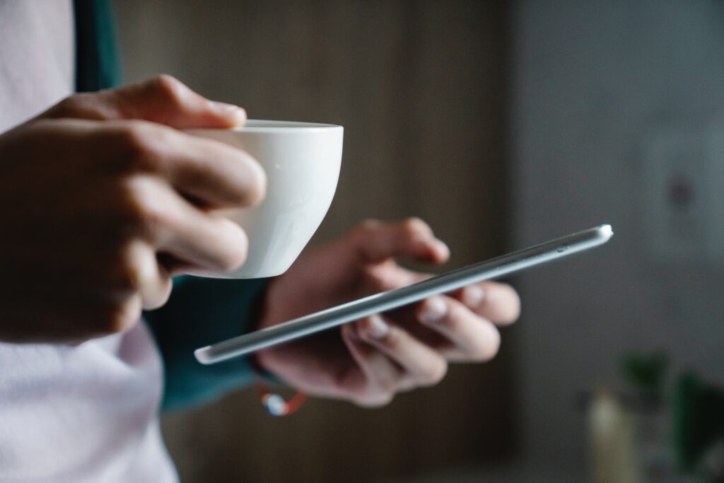 Close up of hands texting holding coffee