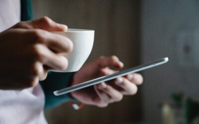 Close up of hands texting holding coffee